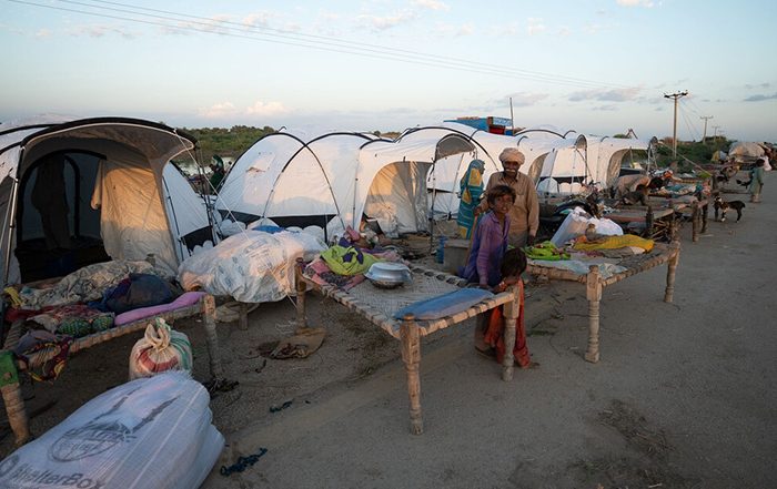 People standing next to tents after flooding in Pakistan