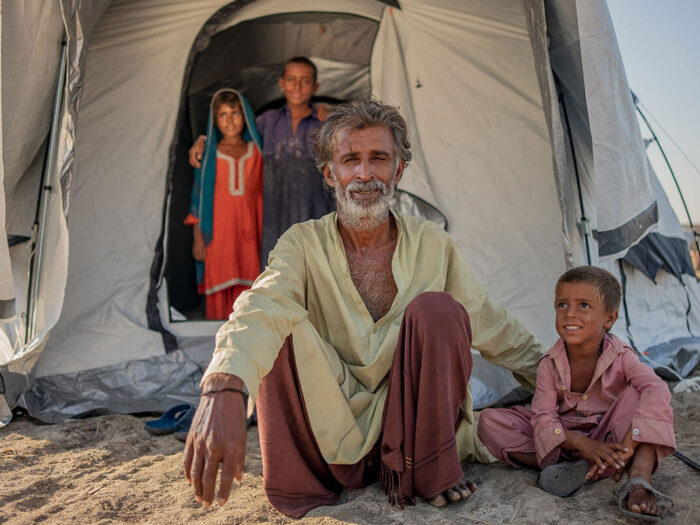 Family smiling outside their emergency relief tent after flooding in Pakistan