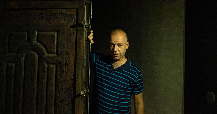 Man leaning on a door in a damaged home in Ukraine