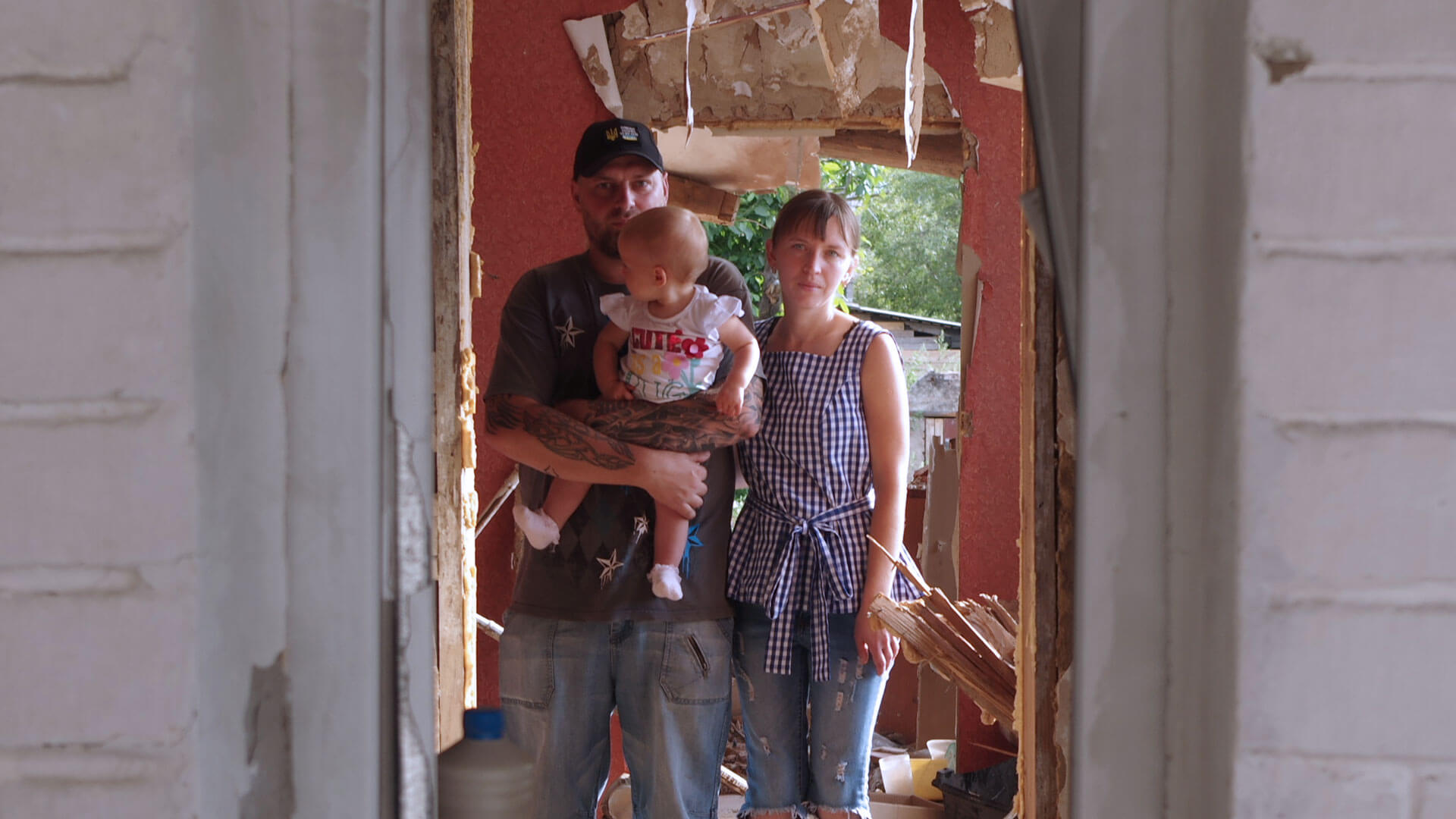 Young family stand in the doorway of their home destroyed in the Ukraine war