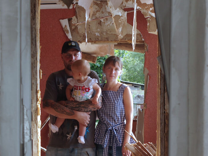 Young family stand in the doorway of their home destroyed in the Ukraine war