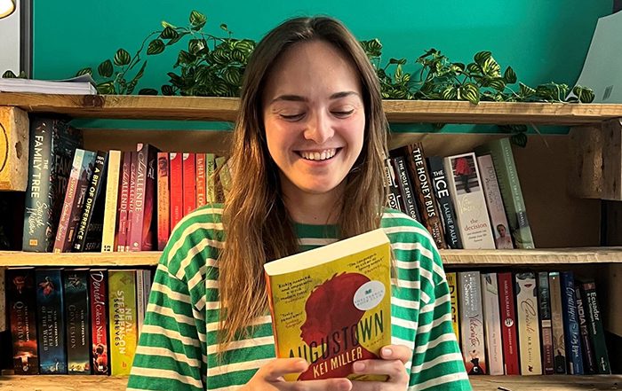 Woman look at back of book in front of a book shelf