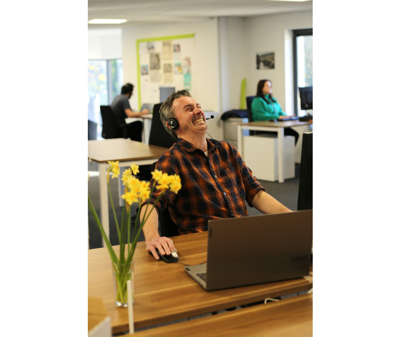 ShelterBox staff member in office laughing while speaking on the phone