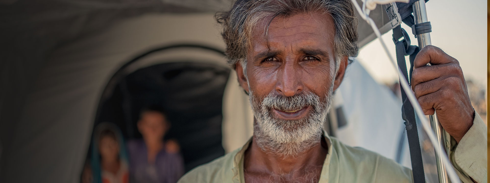 Portrait of Pakistani man standing outside emergency tent