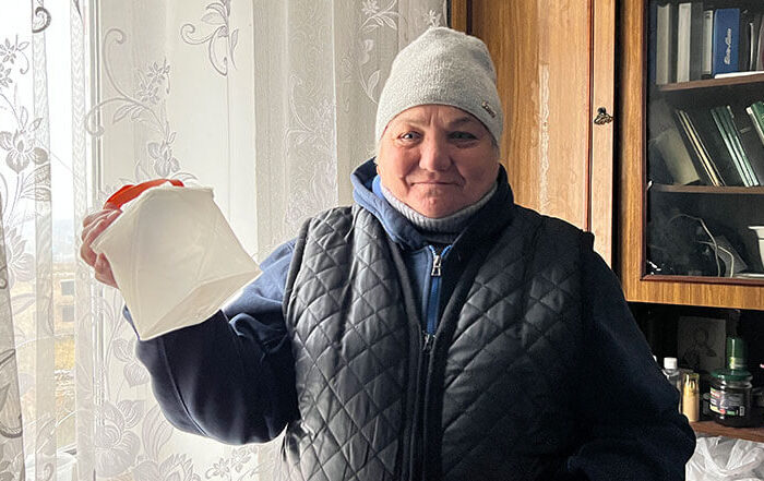 Ukrainian woman in winter hat stands by window
