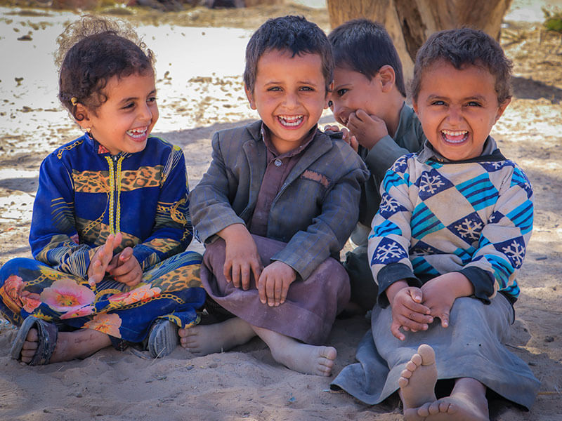 Children sitting on the ground laughing in Yemen
