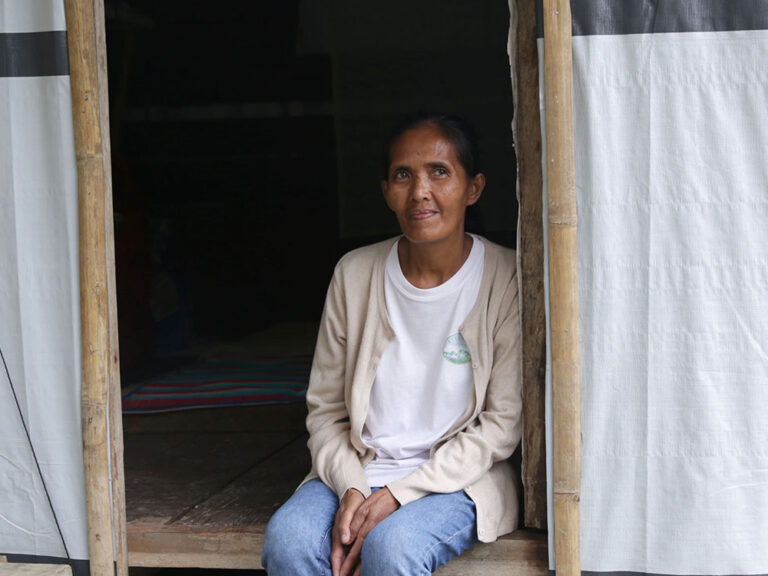 Filippino woman sits in entryway of her emergency shelter