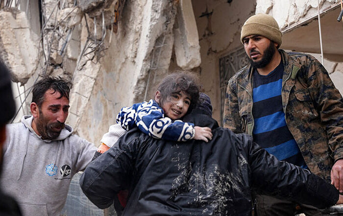 Child being carried from rubble of building after earthquake in Syria