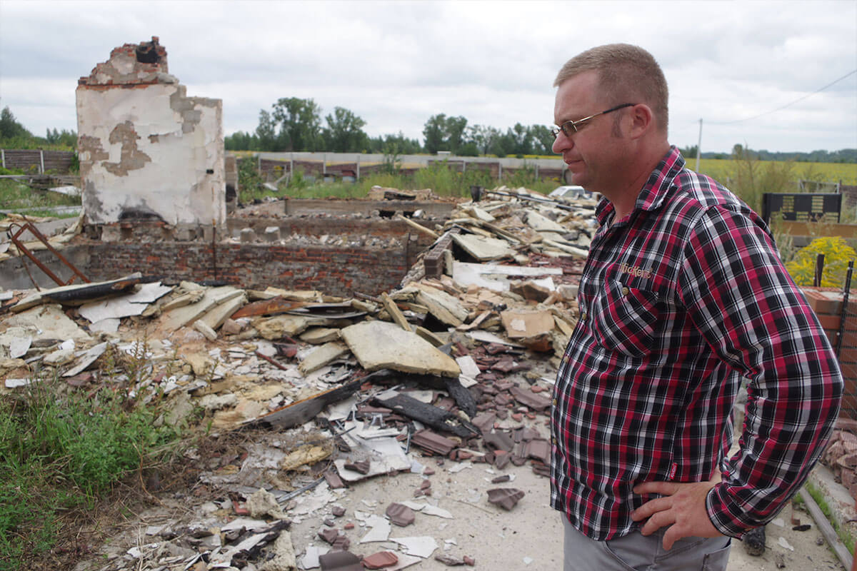 Man looking at rubble of a former house