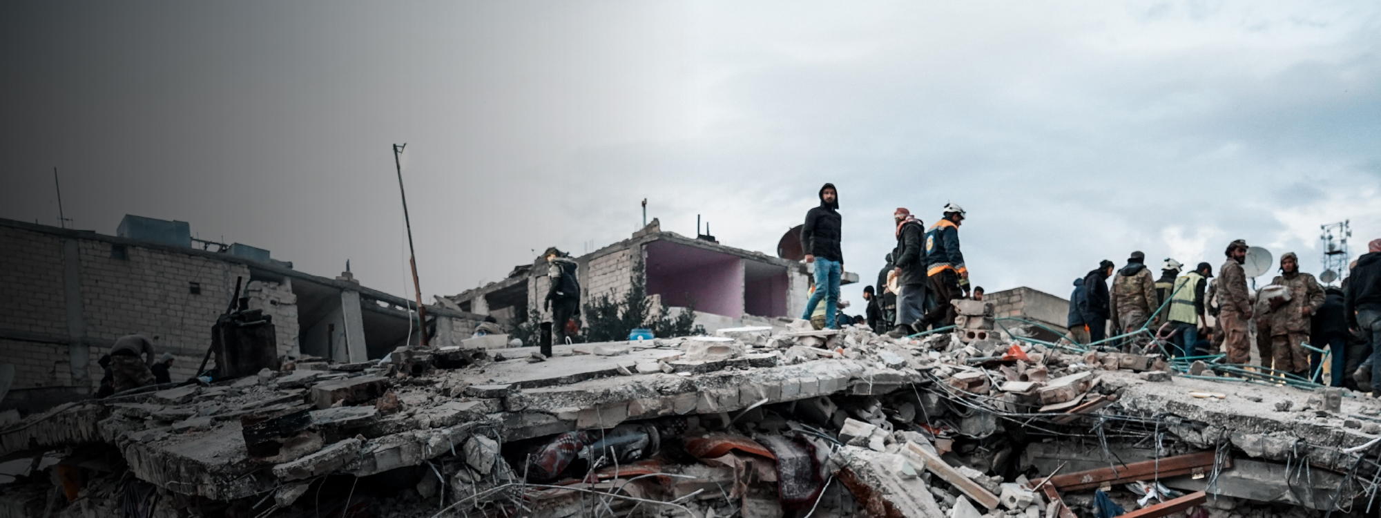Rubble of collapsed buildings in Syria with people standing on them