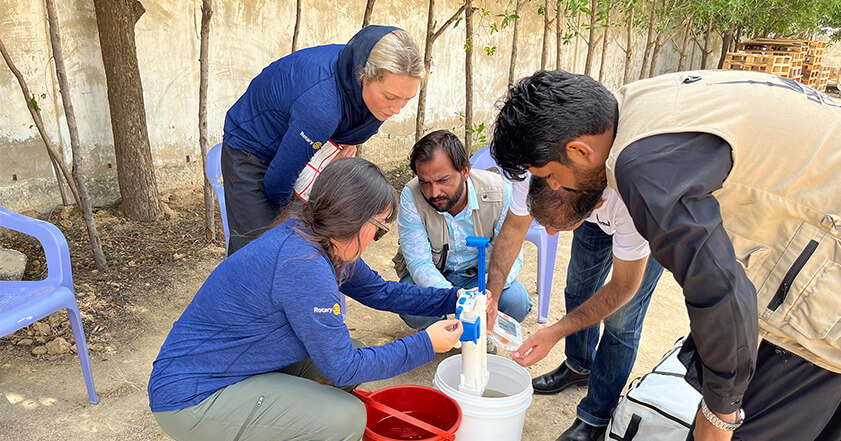 A group of men and women carrying out training on how to use a water filter