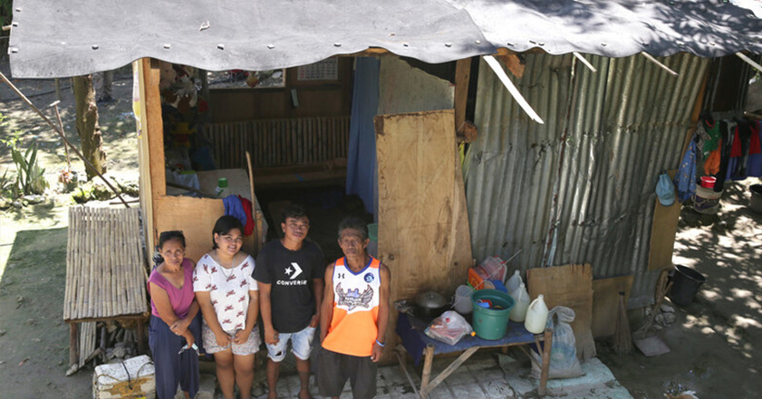 family of four standing outside their home in Cebu