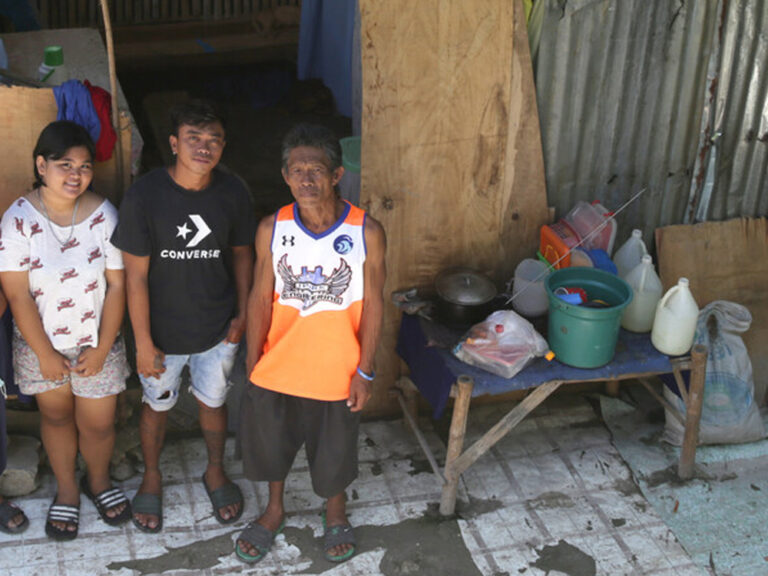 A family of four standing outside their home in the Philippines
