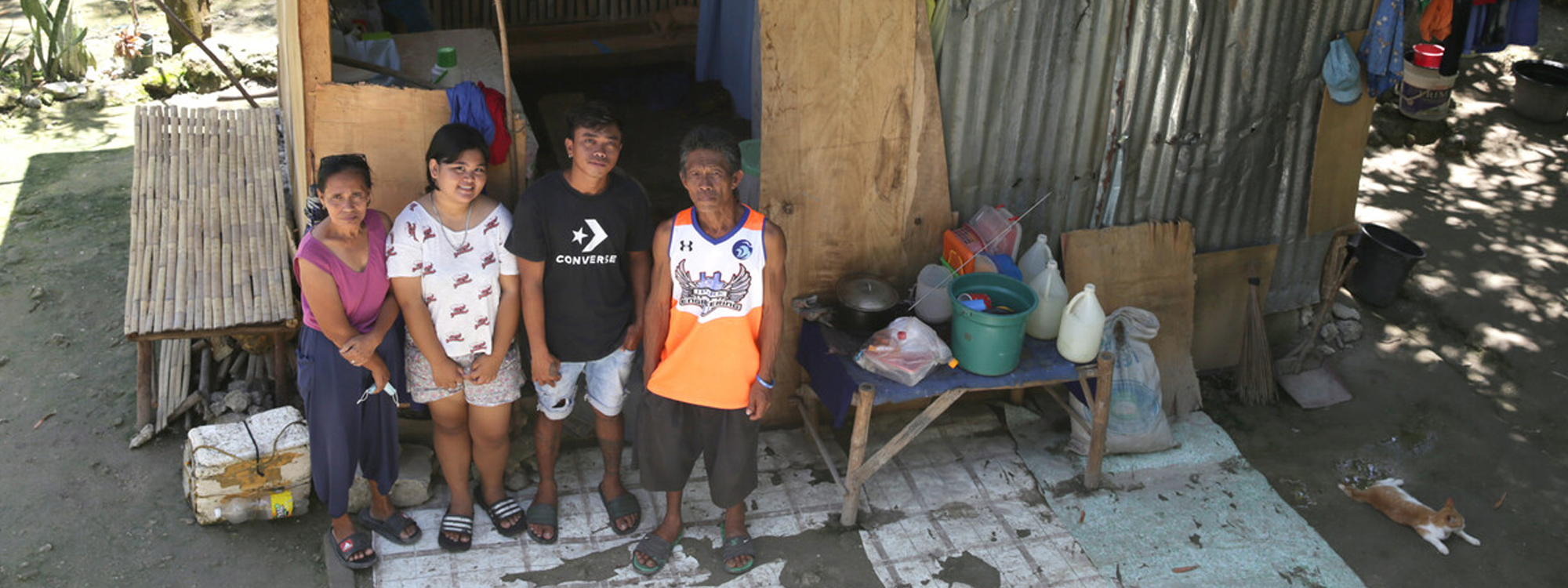 A family of four standing outside their home in the Philippines