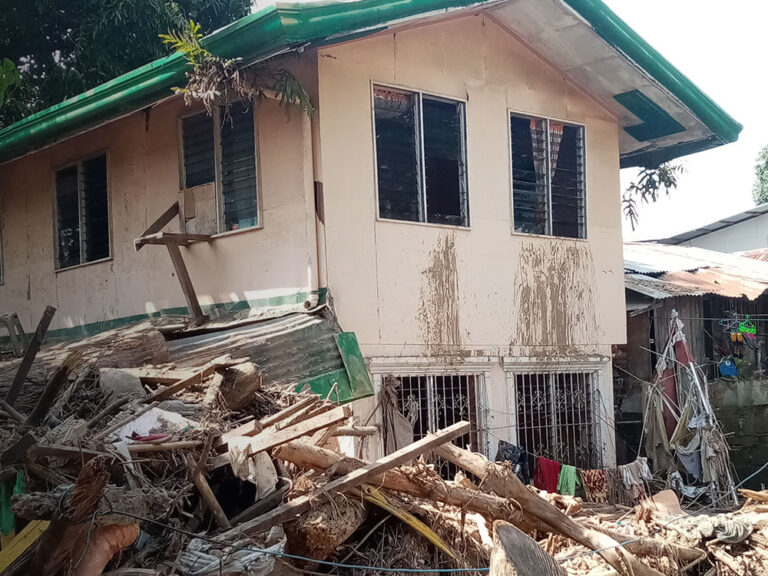 House surrounded by rubble after tropical storm in the philippines