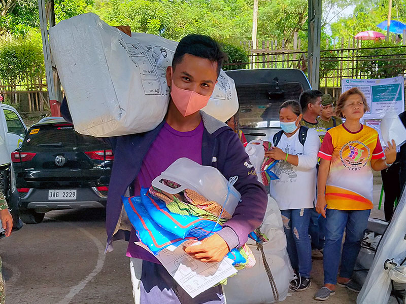 Man in facemask carries shelterbox aid on shoulder in the philippines