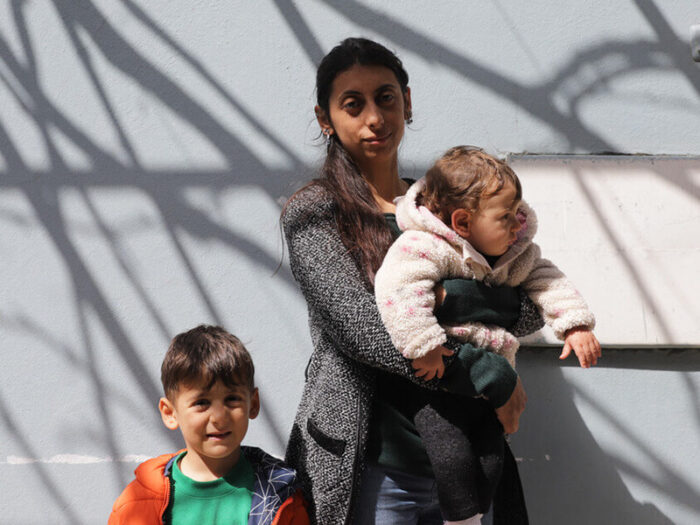 A woman holding her baby daughter with her young son next to her