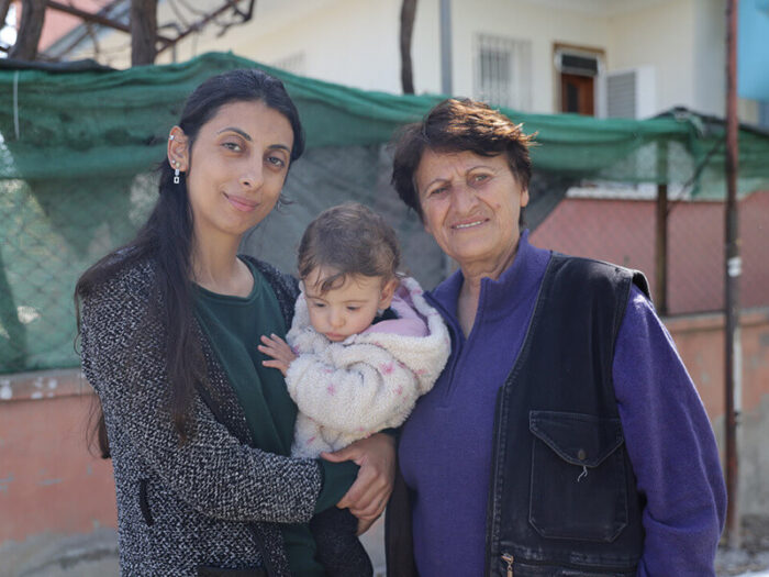 A woman holding her baby daughter, standing next to her mother