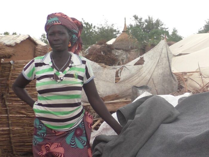 Woman standing next to a shelter in Cameroon