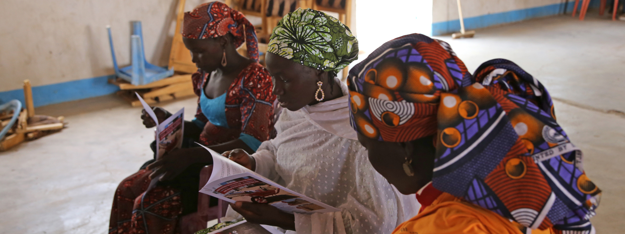 Three women looking sitting and looking at paperwork detailing their stories in Cameroon