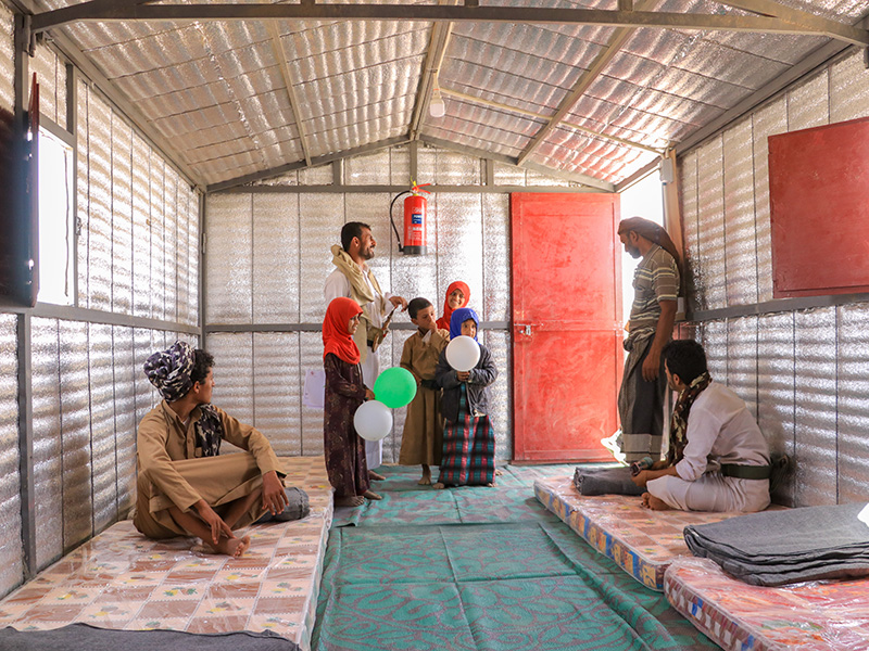 A family standing and sitting inside an iron net shelter