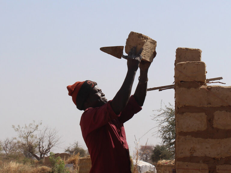 Man placing brick on a partially constructed wall