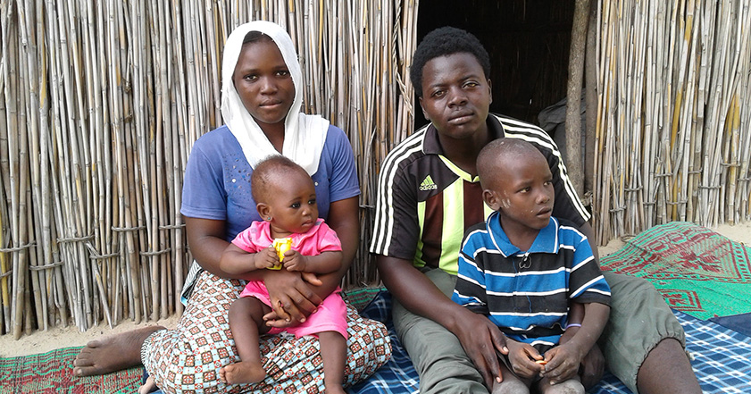 Man, woman and two babies sitting in front of a shelter
