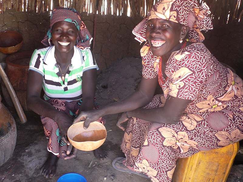 Two ladies sitting inside a shelter and smiling