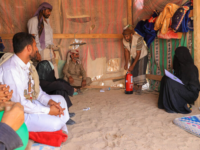 Men and women being trained in using a fire extinguisher inside a shelter