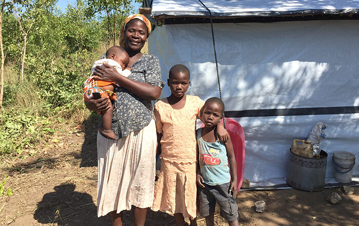 Woman and three children standing in front of a shelter in Malawi