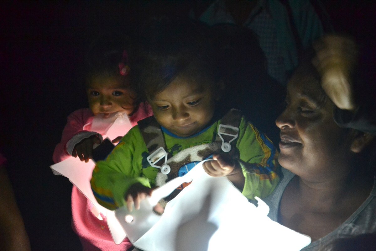 Woman carrying a child who is holding a solar light