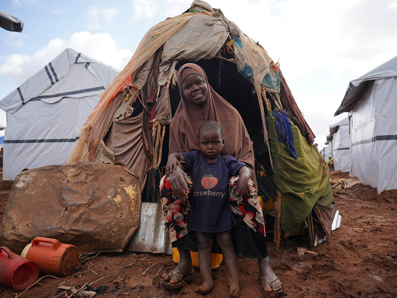 Woman and child next to temporary shelters in a displacement camp in Somalia