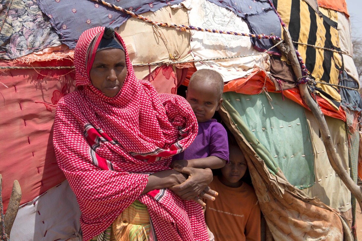 Woman holding a child outside of a temporary shelter in Somaliland