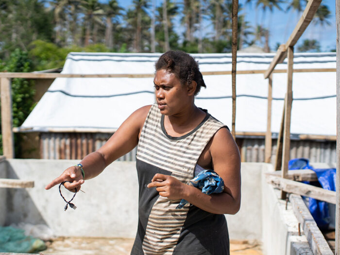 Woman in standing and pointing in a home being rebuilt in Vanuatu