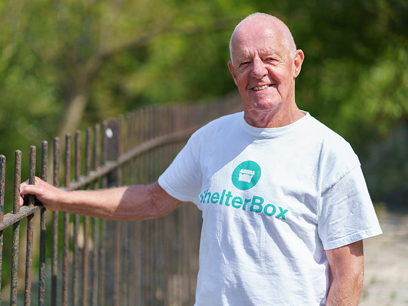 Man wearing ShelterBox t-shirt standing next to some railings