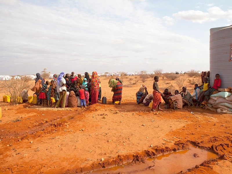 People in desert like conditions with water carriers in Ethiopia