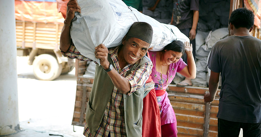 Man and woman carrying a bag of aid in Nepal