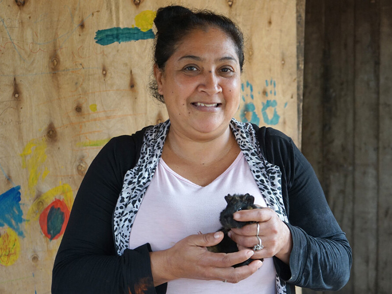 Woman smiling at the camera while holding a black guinea pig