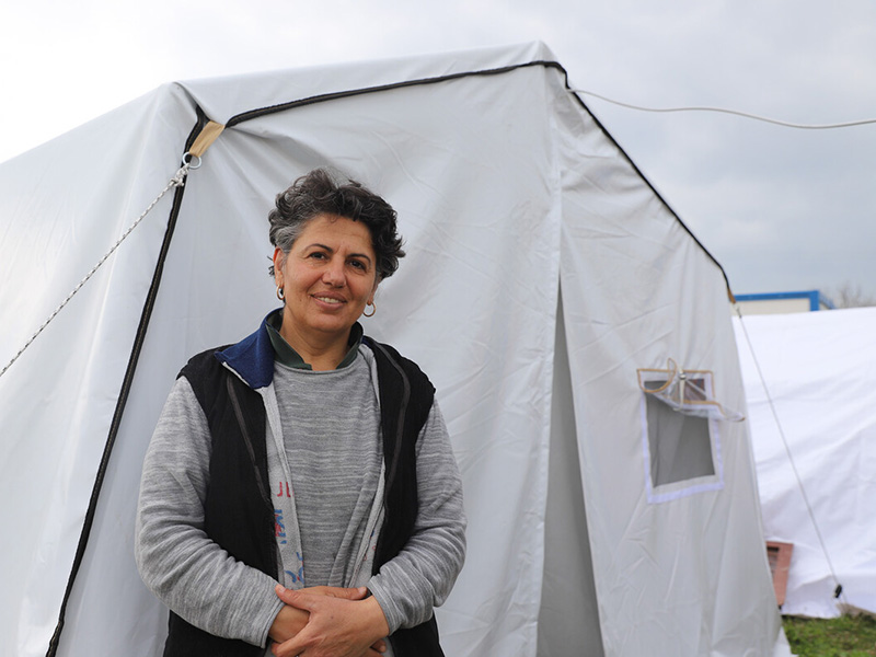 Woman standing outside a tent after the Turkey earthquakes