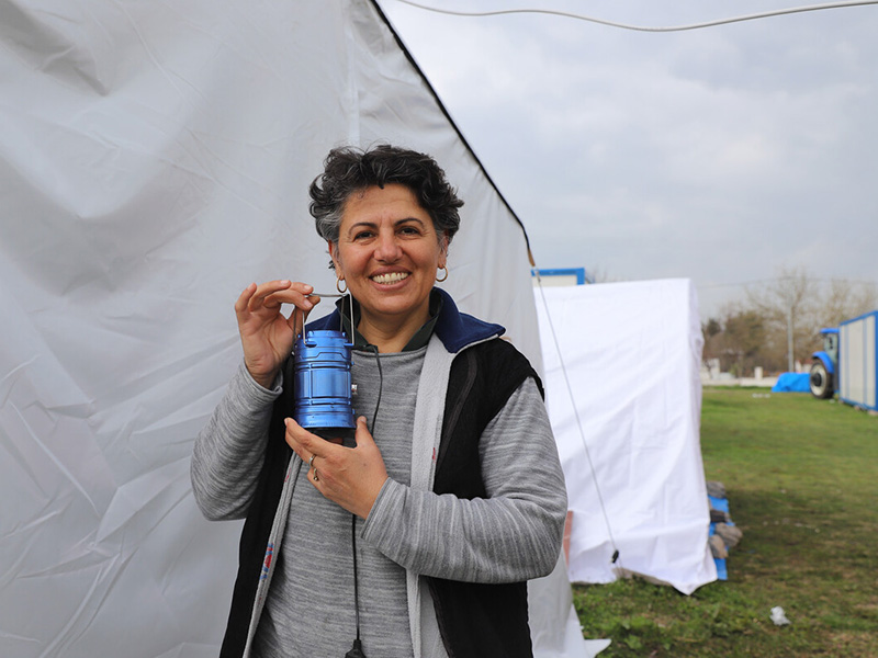 Woman holding a solar light standing outside a tent