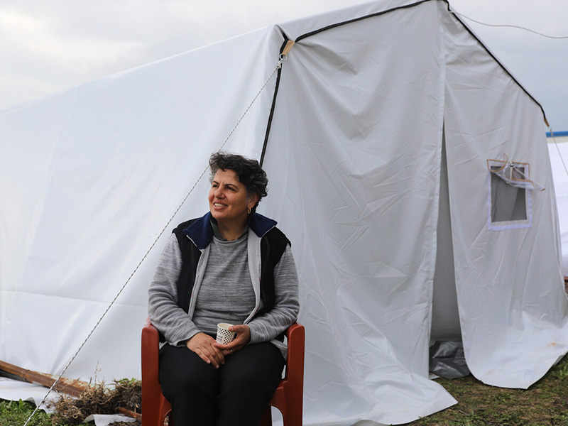 Woman drinking coffee outside a tent after the Turkey earthquakes