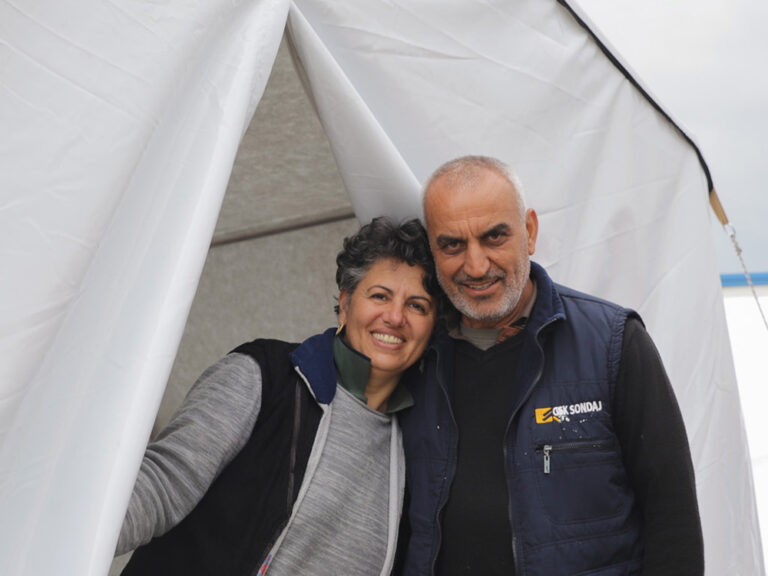 Man and woman standing in the door of a tent after losing their home to the Turkey earthquakes