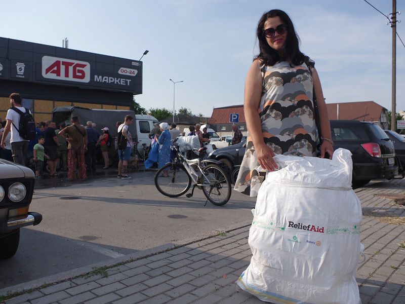 Woman holding bag of aid in front of distributions in Ukraine