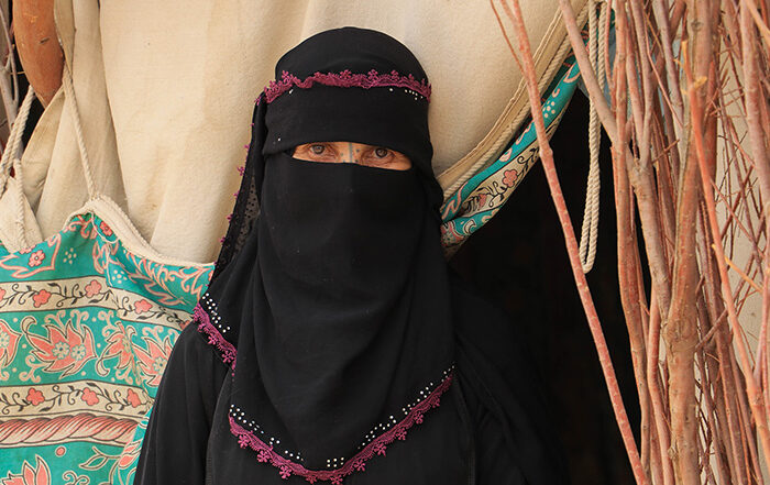 Woman wearing headscarf and face covering in front of a tent in Yemen