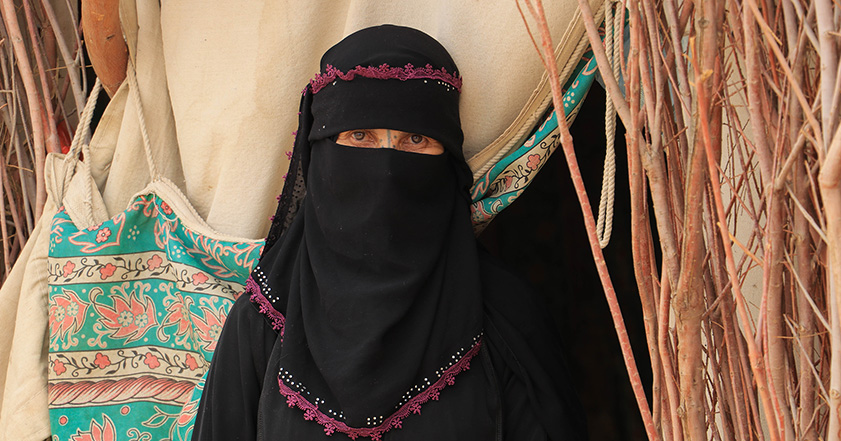 Woman wearing headscarf and face covering in front of a tent in Yemen