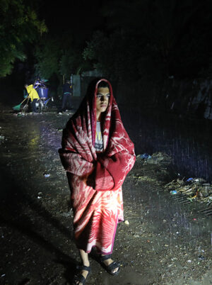Man covered in a blanket standing in heavy rain in Storm Daniel in Libya