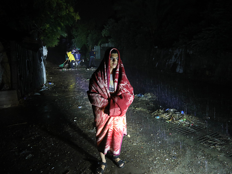 Man covered in a blanket standing in heavy rain in Storm Daniel in Libya