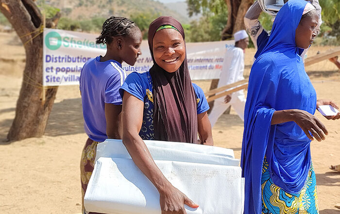 Woman smiling while holding aid in Cameroon