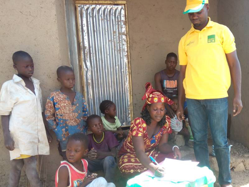Woman signing document surrounded by children and a man standing in Cameroon
