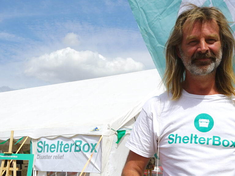 Man wearing ShelterBox t-shirt outside marquee